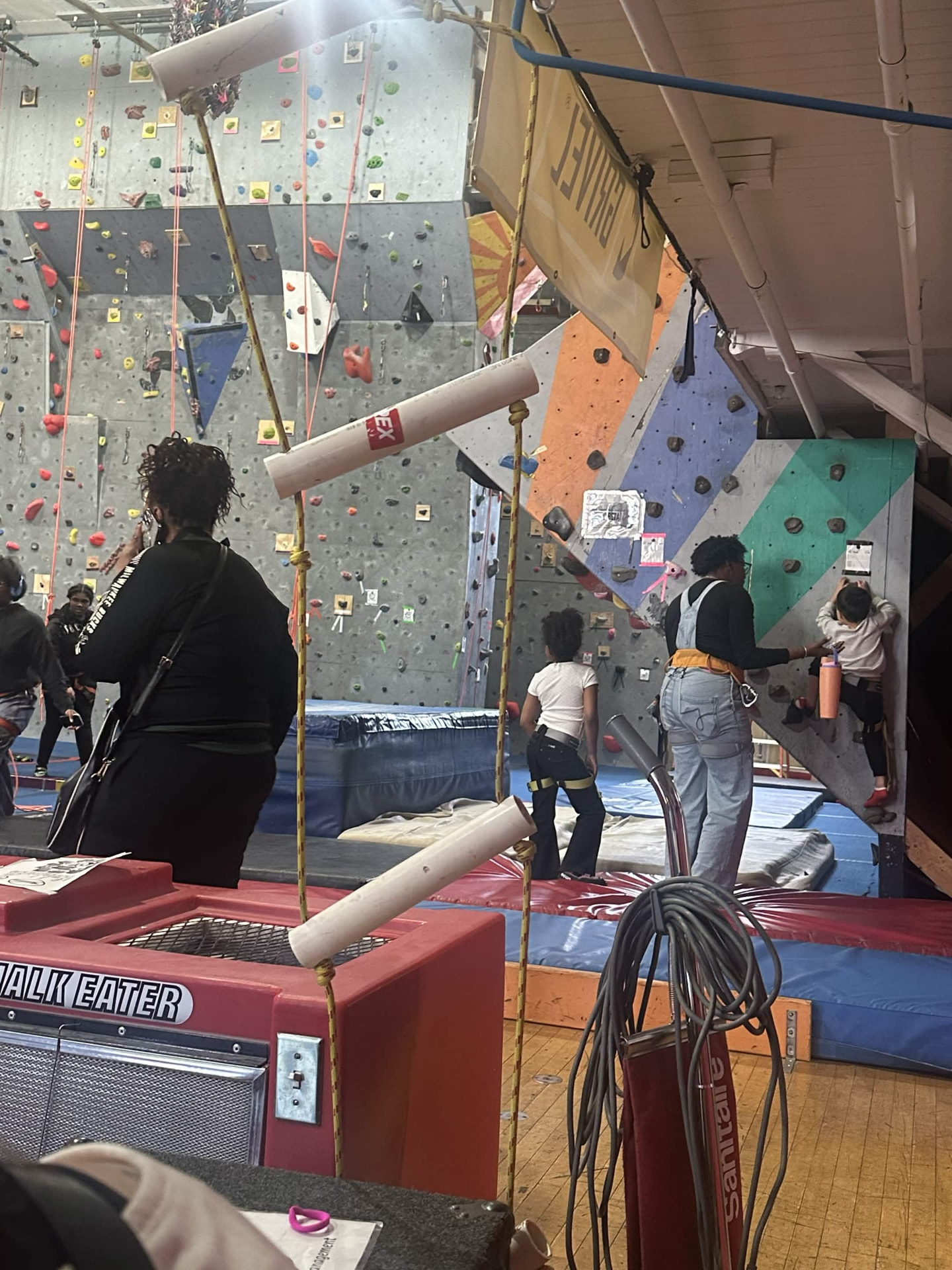 Mentors helping young people get fitted with climbing harnesses.